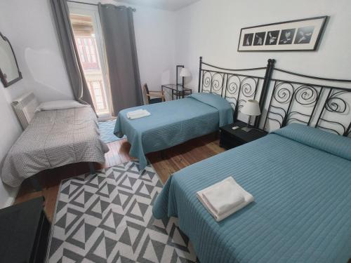 a hotel room with two beds and a chair at La Posada de San Marcial in Tudela
