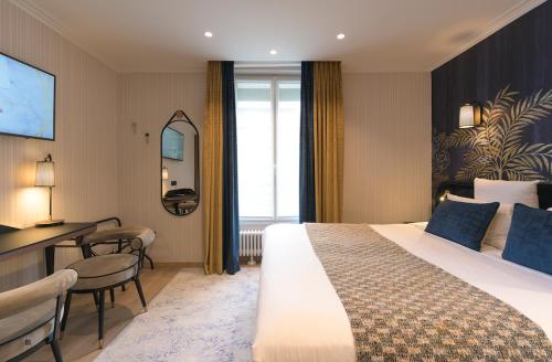 a hotel room with a large bed and a desk at Hôtel Tourisme Avenue in Paris