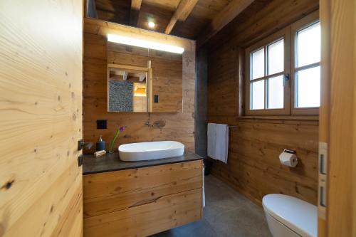a bathroom with wooden walls and a sink and a toilet at Chalet Schafberg in Wildhaus