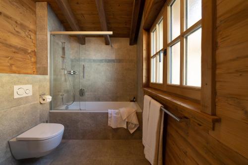 a bathroom with a tub and a toilet and a shower at Chalet Schafberg in Wildhaus