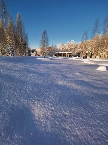 a large snow covered field with a building in the background at Dabas Osta in Jūdaži