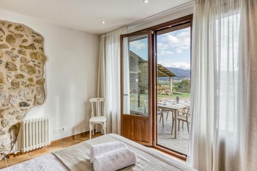Un dormitorio con una cama y un balcón con una mesa. en La Cabanya de la Rovira - Baix, en Joanetes