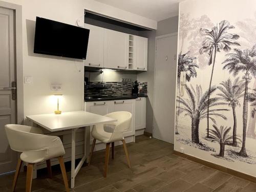 a kitchen with a table and chairs with palm trees on the wall at Eden urbain au centre ville in Chalon-sur-Saône