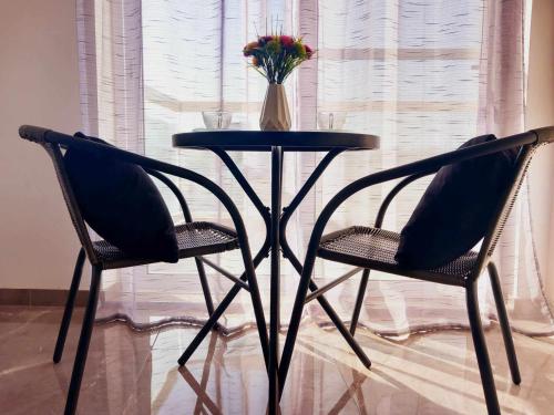 a black table with two chairs and a vase of flowers at Large, 3 Bedroom Apartment in Marsascala in Marsaskala