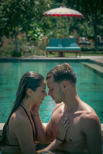 a man and a woman sitting in a swimming pool at Umah Lusa in Munduk