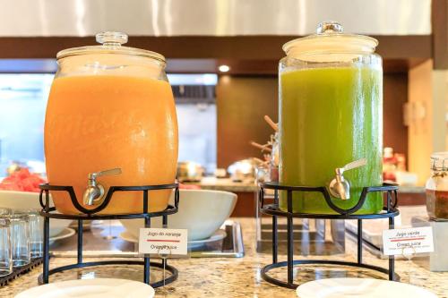 シウダード・デル・カルメンにあるCourtyard by Marriott Ciudad del Carmen Campecheのカウンターの上にオレンジジュースとグリーンジュースの入ったガラス容器が2つある