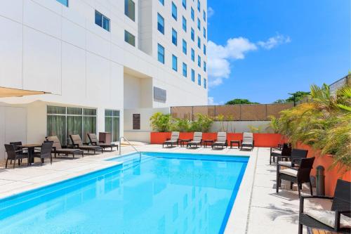 a swimming pool with chairs and a building at Courtyard by Marriott Ciudad del Carmen Campeche in Ciudad del Carmen