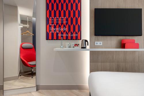 a room with a red chair and a television at Holiday Inn Express Porto - Boavista by IHG in Porto