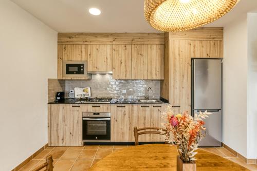 a kitchen with wooden cabinets and a table with a vase of flowers at La Cabanya de La Rovira in Joanetes