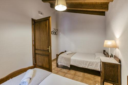 a small room with two beds and a door at La Cabanya de la Rovira - Dalt in Joanetes
