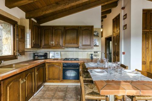 a kitchen with wooden cabinets and a table with chairs at La Cabanya de la Rovira - Dalt in Joanetes