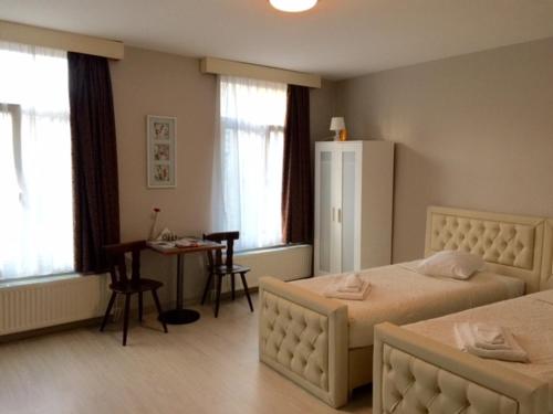 1 dormitorio con 2 camas, mesa y escritorio en Prestige Flats, en Bruselas