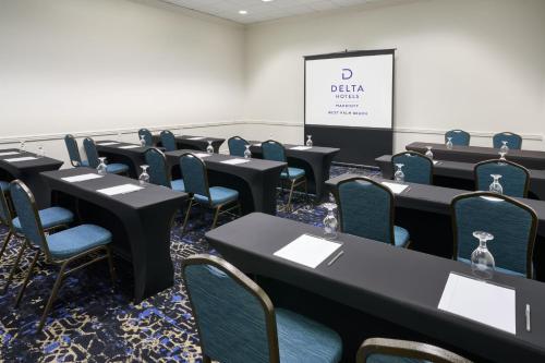 a conference room with tables and chairs and a screen at Delta Hotels by Marriott West Palm Beach in West Palm Beach