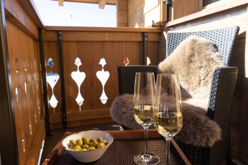 a table with two glasses of wine and a bowl of fruit at Chalet Schibenstoll in Wildhaus