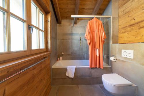 an orange robe is hanging in a bathroom with a tub at Chalet Schibenstoll in Wildhaus