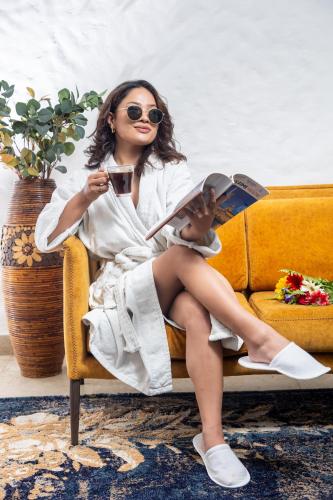 a woman sitting on a couch reading a book at Arushi Boutique Hotel in Kathmandu