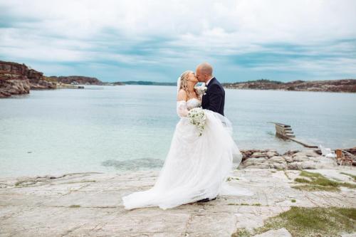 a bride and groom kissing on the rocks by the water at Panorama Hotell & Resort in Steinsland