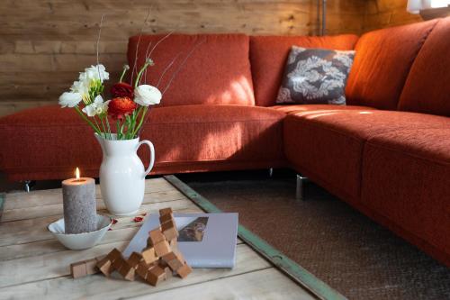 a living room with a red couch and a table with a candle at Chalet Schibenstoll in Wildhaus