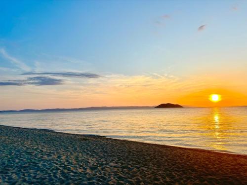 a beach with the sun setting over the water at Candi Luxury Suites 2 in Neos Marmaras