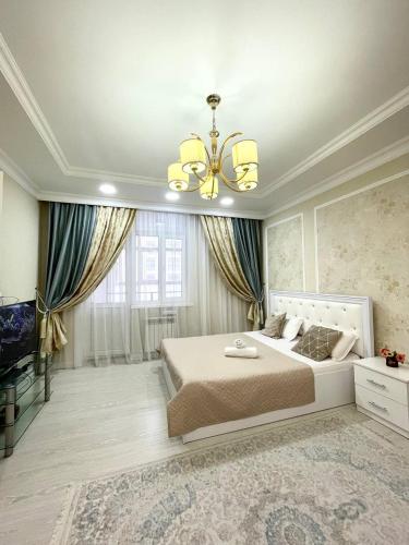 a bedroom with a large bed and a chandelier at Promenade Expo in Prigorodnyy
