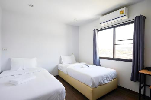 zwei Betten in einem Zimmer mit Fenster in der Unterkunft X GO INN Chiang Mai University - CMU โกอินน์ มหาวิทยาลัยเชียงใหม่ in Chiang Mai