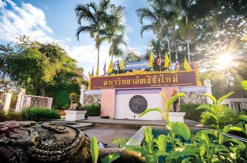 a sign in front of a building with flags at GO INN Chiang Mai University - CMU โกอินน์ มหาวิทยาลัยเชียงใหม่ in Chiang Mai