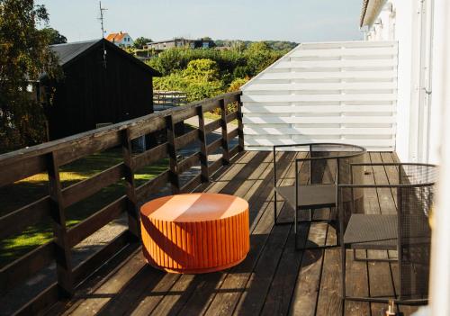 a deck with an orange stool and a table and chairs at The Falcon Hotel in Allinge