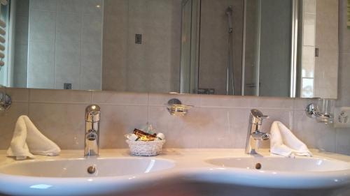 a bathroom sink with two faucets and a mirror at Hôtel Splendide in Crans-Montana