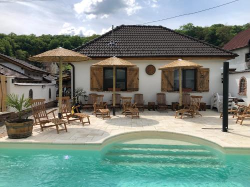 a house with a patio with chairs and a pool at Complex Butoaiele Transilvaniei - Cazare & SPA - Natura - Relaxare in Mediaş