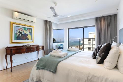 a bedroom with a large white bed with a window at Atlantic Sky Penthouses 3-Bedroom and Studio with Breathtaking Views in Cape Town