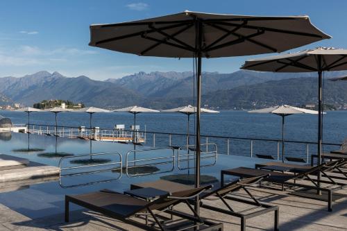 a pool with chairs and umbrellas next to the water at Hotel La Palma in Stresa