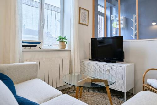 un salon avec une télévision et une table en verre dans l'établissement Maison 2 chambres terrasse à Marcq en Baroeul., à Marcq-en-Barœul