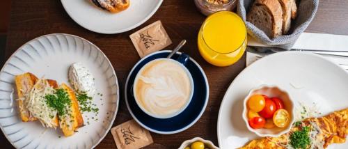 a table with plates of food and a cup of coffee at Room42 - Suites & Apartments in Esztergom