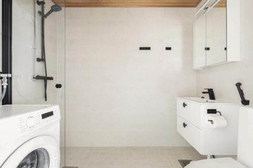 a bathroom with a washing machine and a shower at Kotimaailma Apartments Pukkila - New studio for 2 in Turku