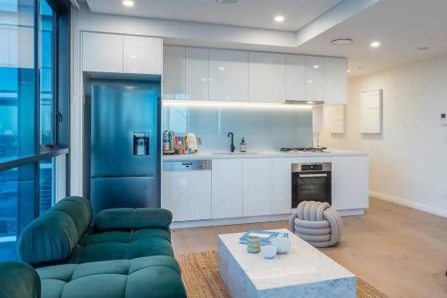a living room with a green couch and a kitchen at Utopia City Oasis Exquisite Urban Retreat in Brisbane