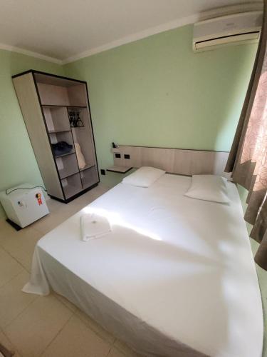 a large white bed in a room with a mirror at Hotel Globo in Cianorte
