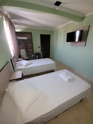 a hotel room with two beds and a flat screen tv at Hotel Globo in Cianorte
