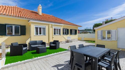 a patio with a table and chairs in front of a house at Casa da Roseira by LovelyStay in Sintra