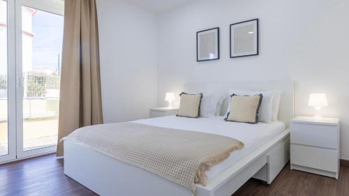 a white bedroom with a bed and a window at Casa da Roseira by LovelyStay in Sintra