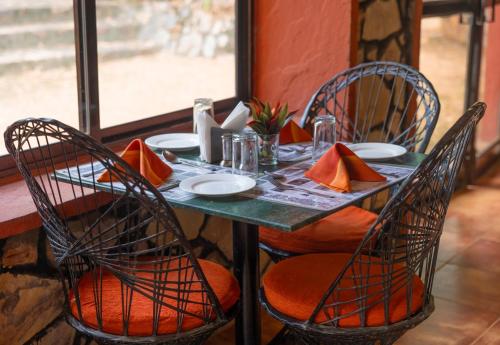 Indian Adventures Tiger Moon resort في Khilchīpur: طاولة مع كراسي وطاولة خضراء مع وسائد برتقالية