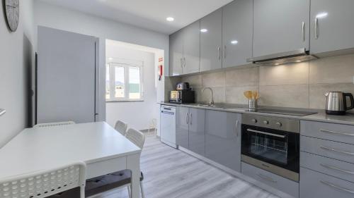 a kitchen with white cabinets and a white table at Casa da Roseira by LovelyStay in Sintra