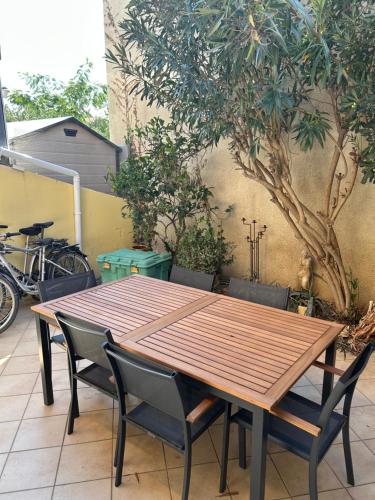 une table et des chaises en bois assises à côté d'un arbre dans l'établissement Maison face a la mer, à Sainte-Marie-la-Mer