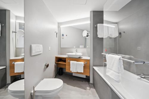 a bathroom with a sink and a toilet and a mirror at Limehome Basel Münzgasse in Basel