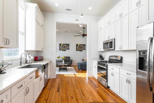 a kitchen with white cabinets and a wooden floor at 3BR Cottage on Carondelet by Hosteeva in New Orleans