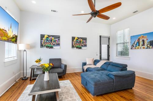 a living room with a blue couch and a ceiling fan at 3BR Cottage on Carondelet by Hosteeva in New Orleans