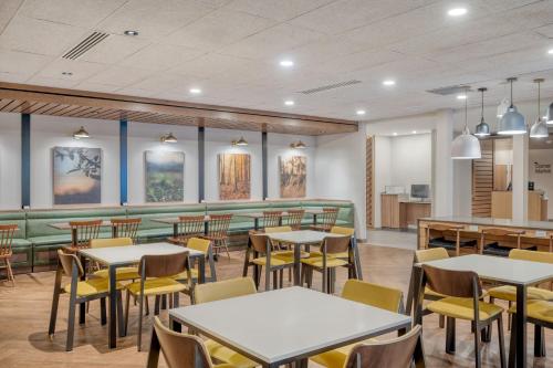 a restaurant with tables and chairs and a green couch at Fairfield by Marriott Inn & Suites Shelbyville in Shelbyville