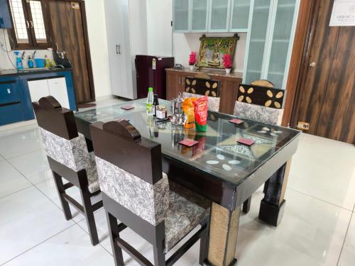 a dining room with a glass table and chairs at Orraica Stays Vajra Rao Luxe in Gundipet