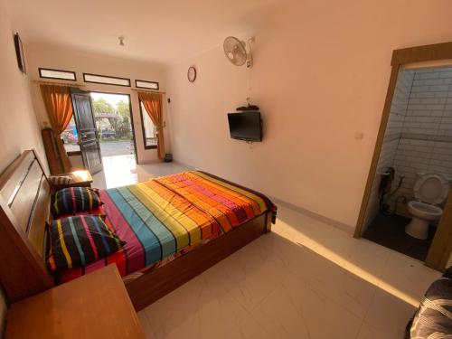 a bedroom with a bed with a colorful blanket at Kamar no 2 in Sampal 2