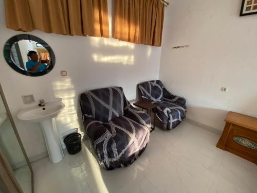 a bathroom with two chairs and a sink and a mirror at Kamar no 2 in Sampal 2