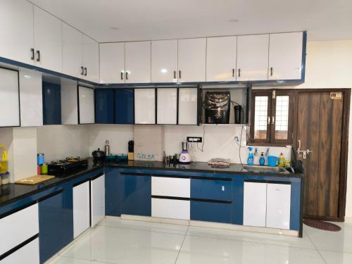 a large kitchen with blue and white cabinets at Orraica Stays Vajra Rao Luxe in Gundipet